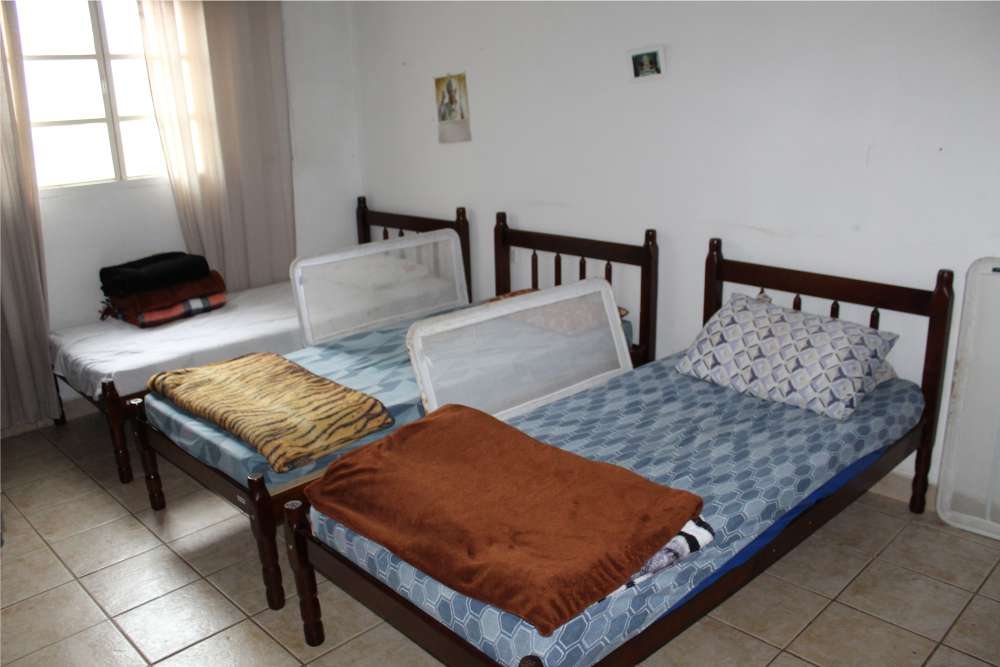 Quarto com três camas arrumadas e janela