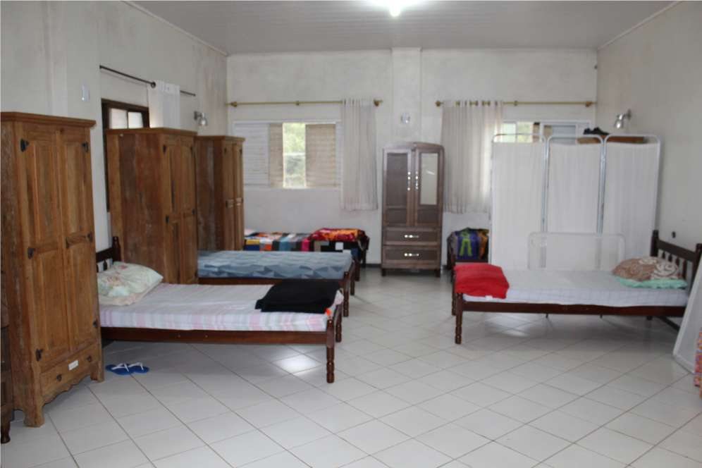 Quarto com camas, guarda-roupas de madeira e janelas