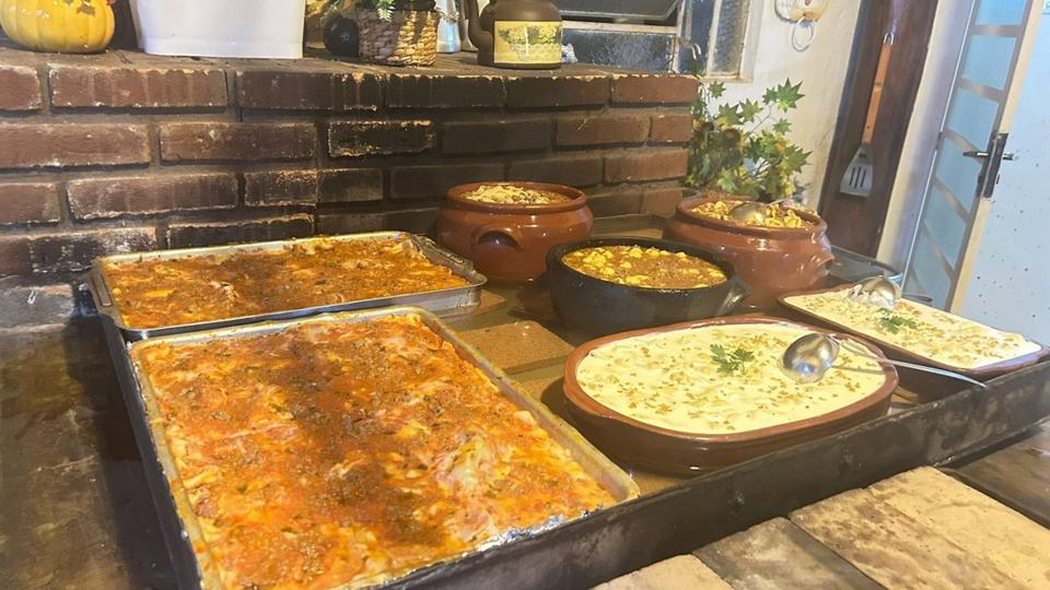 Travessas de massas e lasanhas servidas num jantar beneficente
